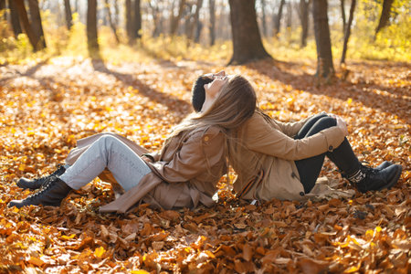 Two girls friends spending time together in autumn parkの写真素材