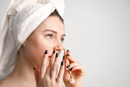 Caucasian girl with towel on a head using roller isolated on white background
