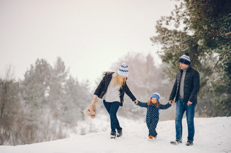 Little girl with parents playing in a winter parkの写真素材