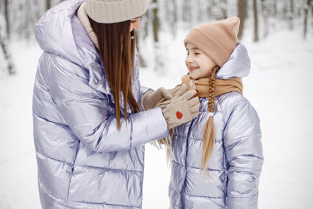 Brunette mother and and her daughter standing in winter forest