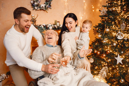 Mother, father, little son and old grandfather on a wheelchair sitting near Christmas treeの写真素材
