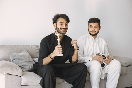 Two men sitting on a couch and watching football on laptop