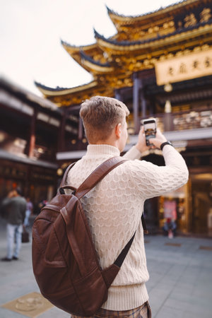 male tourist taking photos of a pagoda at Yuyuan market in Shanghaiの写真素材
