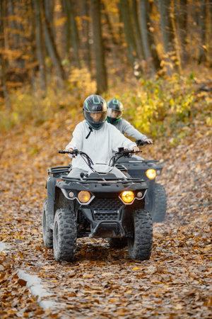 Man and woman driving quad bike in autumn forest