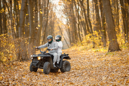 Man and woman driving quad bike in autumn forest