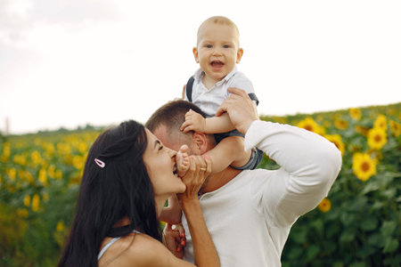 Beautiful family and child with sunflower in spring field