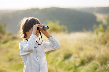 Little boy standing in a field with a binoculars at summerの写真素材