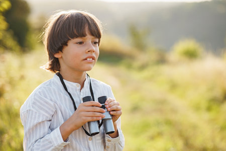 Little boy standing in a field with a binoculars at summerの写真素材