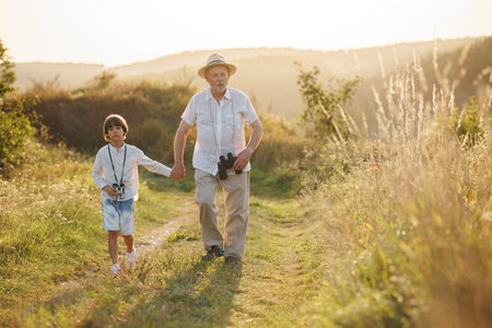 Photo of a little boy with his grandfather walking in a field at summerの写真素材