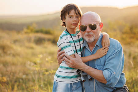 Little boy with his grandfather standing in a field and hugging at summerの写真素材