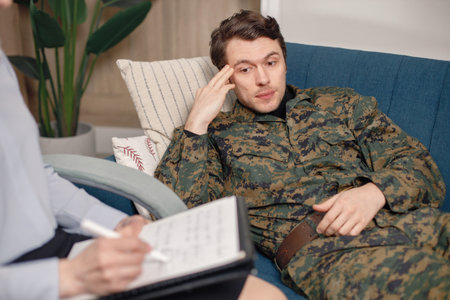 Soldier in military uniform talking to psychiatrist at therapy sessionの写真素材