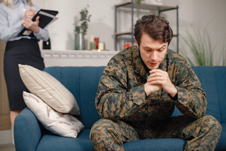 Soldier in military uniform talking to psychiatrist at therapy sessionの写真素材