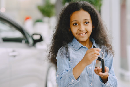 Cute african girl in a blue shirt in a car salonの写真素材
