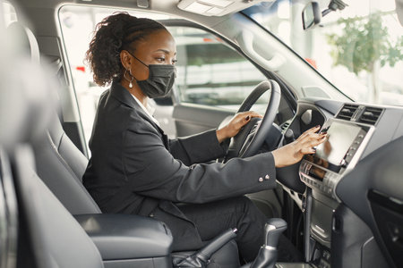 Portrait of black female driver in a car wearing face maskの写真素材