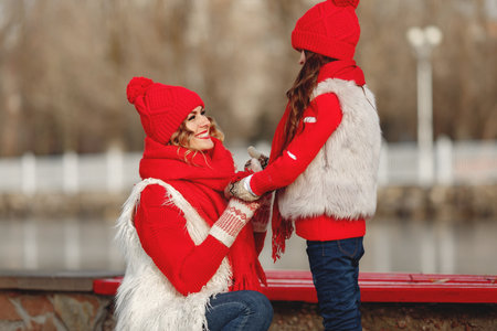 Mother and child in knitted winter hats play in winter parkの写真素材