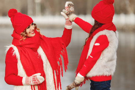 Mother and child in knitted winter hats play in winter parkの写真素材