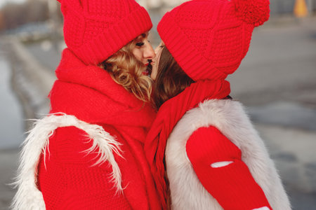 Mother and child in knitted winter hats play in winter parkの写真素材