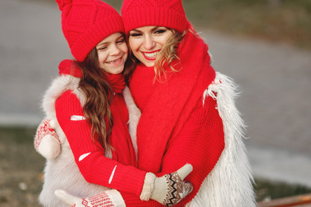 Mother and child in knitted winter hats play in winter parkの写真素材