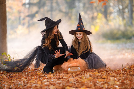 Portrait of mother and daughter in witch costumes in autumn forestの写真素材