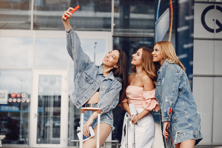 Three beautiful girls standing by the airportの写真素材