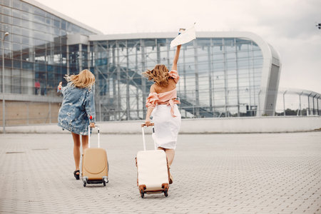 Two beautiful girls standing by the airportの写真素材