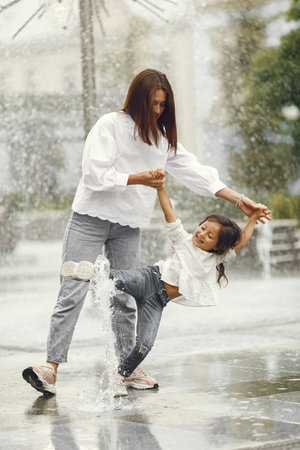 Mom and her little daughter playing by the spray of water