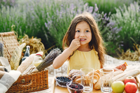 Cute little girl sitting in a picnic in a lavender fieldの写真素材