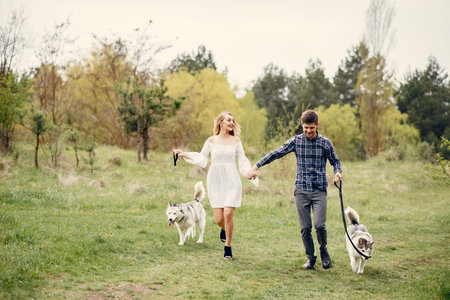 Beautiful couple in a summer forest with a dogsの写真素材