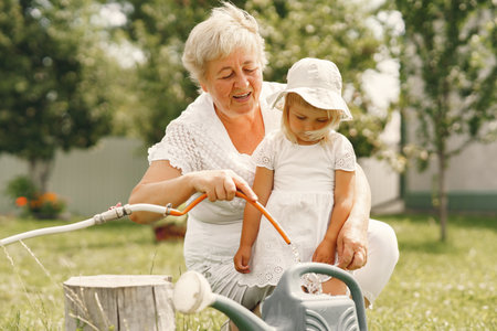 Little girl and her grandmother watering flowers in gardenの写真素材
