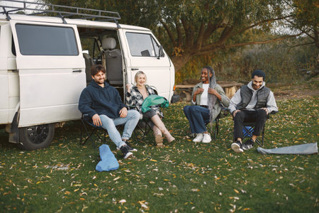 Mulri ethnic friends sitting in camping chairsの写真素材