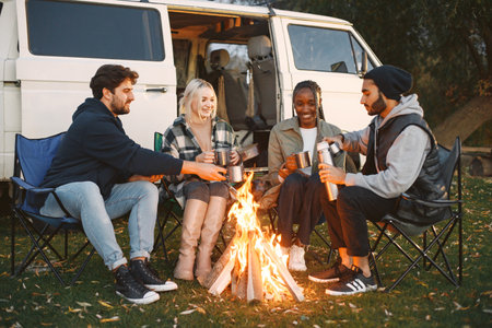 Multi racial people drink coffee by bonfireの写真素材