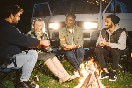 Multi ethnic friends having picnic by campfireの写真素材
