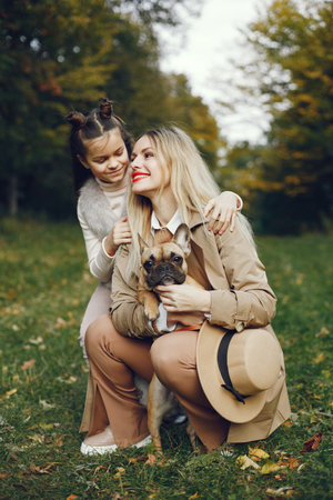 Mother and her daughter with a little puppy french bulldog in a parkの写真素材