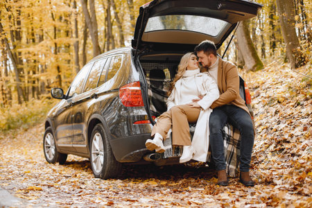 Lovely couple sitting inside car trunk in autumn forestの写真素材