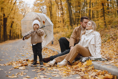Beautiful young family on a walk in autumn forestの写真素材