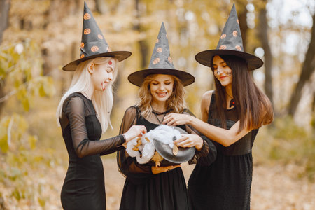 Three witches in forest on Halloween holding a cauldronの写真素材