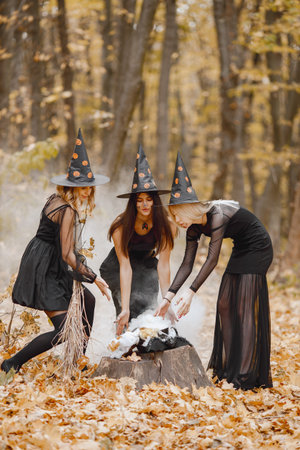 Three witches in forest on Halloween make magic potion