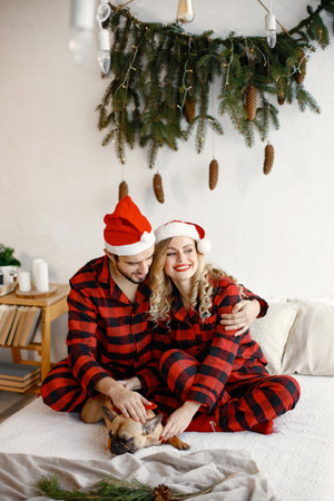 Couple wearing christmas red pajamas with dog on bedの写真素材