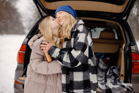 Portrait of a woman standing near open car trunk in winter forestの写真素材