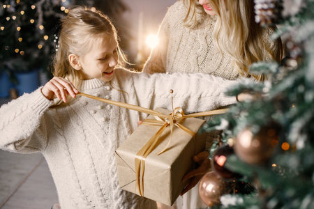 Cropped photo of a little girl standing near christmas tree at home with her motherの写真素材