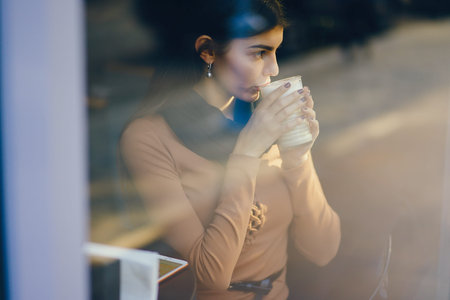 brunette girl drinking a hot beverage at a restaurant