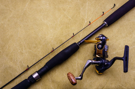 Spinning rod with fishing reel on the background of tarpaulin. Fishing tackle on tarpaulin.