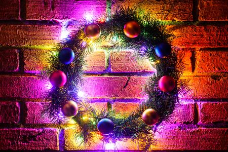 Wreath and garlands of colored light bulbs.Christmas background with lights and free text space. Christmas lights border. Glowing colorful Christmas lights on a brick wall background. New Year.の写真素材