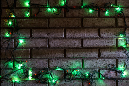 Wreath and garlands of colored light bulbs.Christmas background with lights and free text space. Christmas lights border. Glowing colorful Christmas lights on a brick wall background. New Year.の写真素材