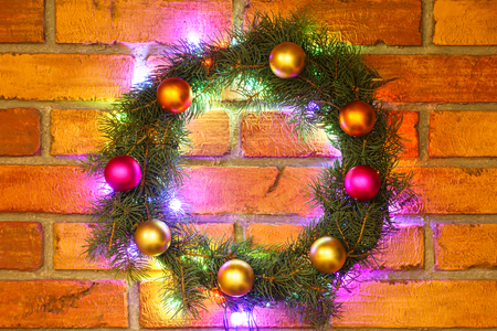 Wreath and garlands of colored light bulbs.Christmas background with lights and free text space. Christmas lights border. Glowing colorful Christmas lights on a brick wall background. New Year.の写真素材