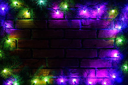 Wreath and garlands of colored light bulbs.Christmas background with lights and free text space. Christmas lights border. Glowing colorful Christmas lights on brick wall background. New Year. の写真素材