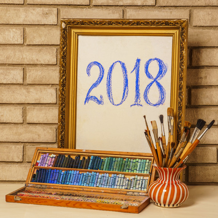 Vase with artistic brushes, pastels and the frame on the background of old brick wallの写真素材