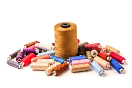 Colored bobbins on white background. Colorful cotton yarns on rolls for sewing.