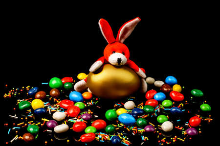 Easter bunny with delicious easter egg and sweets on black backgroundの写真素材