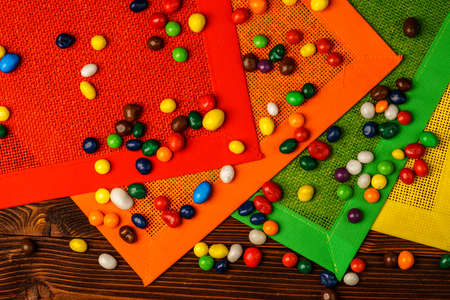 Colorful candies on wooden table with colored napkinsの写真素材